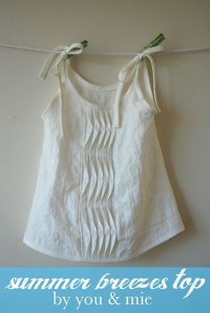 a white top hanging on a clothes line with two green pins attached to the front