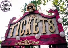 a wooden sign that says tickets with a skull on it's head and lights around the letters