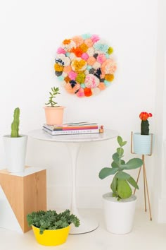 a white table topped with potted plants next to a round wall hanging on the wall