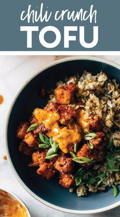 a blue bowl filled with rice and meat covered in sauce on top of a white table