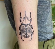 a beetle tattoo on the left arm