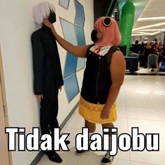 two people standing next to each other in front of a wall with the words tidakk daijobu on it