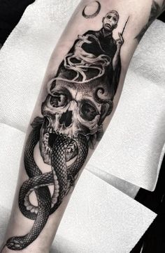 a man with a skull and snake tattoo on his arm is shown in black and white