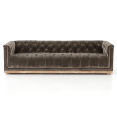 a brown velvet couch with wooden legs and buttons on the back, in front of a white background