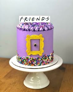 a purple cake with sprinkles and a sign that says friends