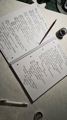 an open notebook with writing on it next to a fountain pen and ink rollers