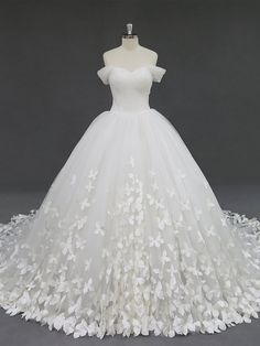 a white wedding dress with flowers on the skirt and off - shouldered neckline