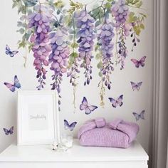 purple flowers and butterflies are hanging from the wall next to a white dresser in a bedroom