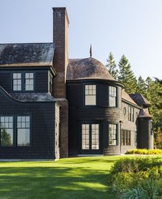 a large black house sitting on top of a lush green field