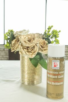 a white table topped with a vase filled with flowers next to a bottle of paint