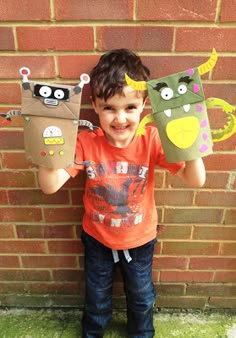 a young boy holding up two paper monsters