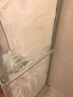 a bathroom with a glass shower door and tile flooring on the wall behind it