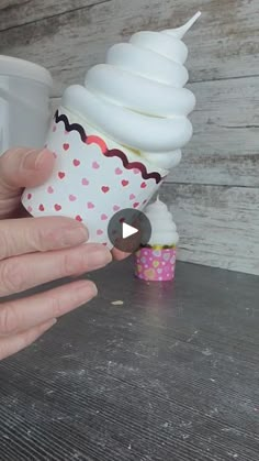 a person is holding a cupcake in front of a lightbulb on a table