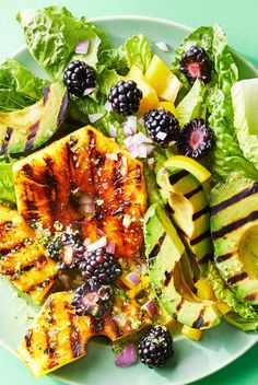 a salad with grilled chicken, fruit and avocado is on a plate