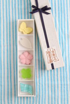 an open gift box with four cookies in it next to a blue and white striped tablecloth