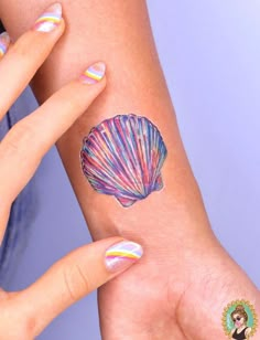 a woman's arm with a colorful shell tattoo on the left side of her wrist