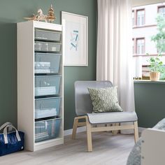 a room with blue walls and pink storage bins on the shelves in front of a window