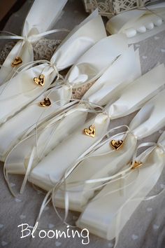 white wedding favors with gold hearts on them and ribbons tied around the edges, sitting on a table