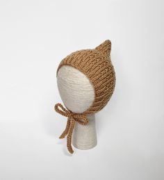 a knitted cat hat on a mannequin's head with a bow