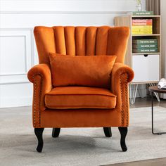 an orange chair sitting in front of a book shelf on top of a carpeted floor