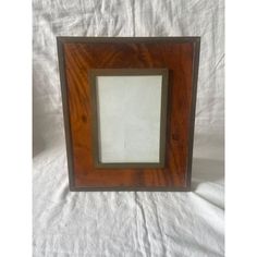 a wooden frame with white paper in the center on a white sheeted cloth background