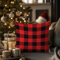 a red and black pillow sitting on top of a couch next to a christmas tree