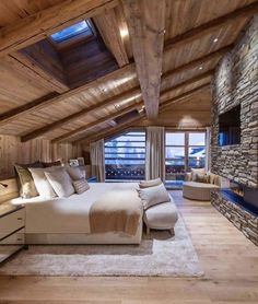 a large bed sitting in the middle of a bedroom next to a stone fire place