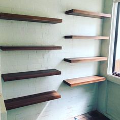 several wooden shelves are lined up against a white brick wall in an otherwise empty room