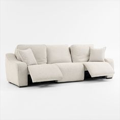 a white couch with pillows on the back and arm rests in front of a white wall