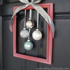 a red frame with ornaments hanging from it's side and a bow on the front door