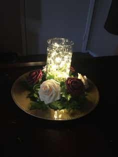 a lighted candle sits on a plate with flowers