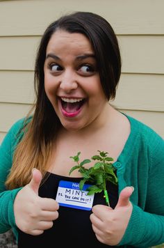 a woman holding a plant and giving the thumbs up