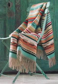 a blanket sitting on top of a chair next to a green wooden door and floor