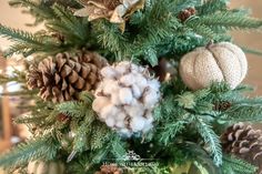 a close up of a christmas tree with cotton balls and pine cones on it's branches