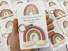 a person holding up some earrings in front of several cards with rainbows on them