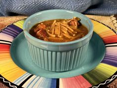 a blue bowl filled with soup on top of a colorful plate