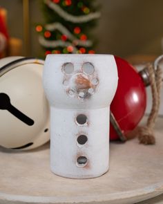 a white object sitting on top of a table next to a red ball and christmas tree