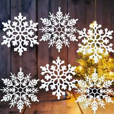 white snowflakes hanging from strings next to a small christmas tree on a wooden table