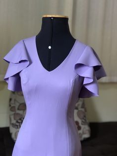 a mannequin wearing a purple dress with ruffles on the sleeves and shoulders