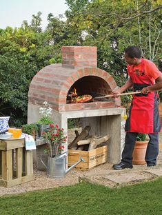 a man in an apron is cooking food on the outdoor brick pizza oven with potted plants