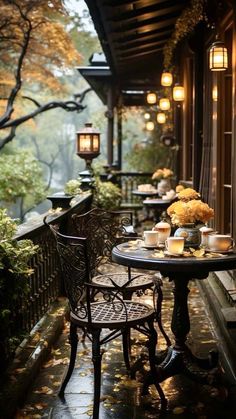 an outdoor table and chairs on a porch with lanterns hanging from the ceiling above it