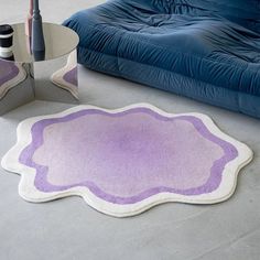 a purple and white rug sitting on top of a floor next to a blue couch