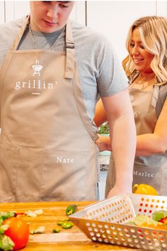 two people in aprons preparing food on a cutting board