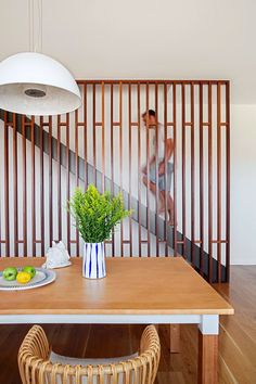 a dining room table with a vase on it and a man walking up the stairs