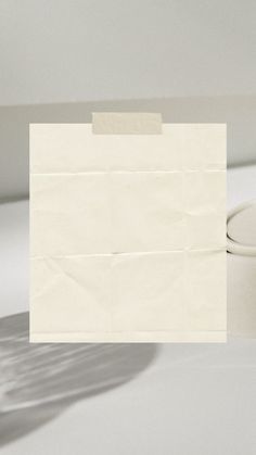 a piece of white paper sitting on top of a table next to a cup and saucer