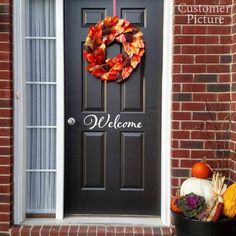 a black front door with a happy thanksgiving wreath on it and pumpkins sitting outside