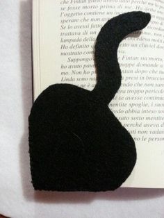 an image of a black cat that is on top of a book with it's tail curled up