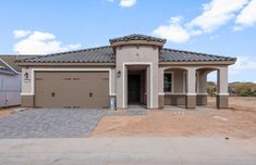 a large house in the middle of a dirt lot with two garages on each side