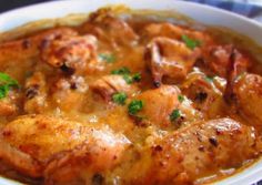 a white bowl filled with chicken covered in gravy and garnished with parsley