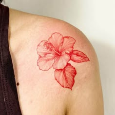 a woman's shoulder with a red flower tattoo on her left arm and chest